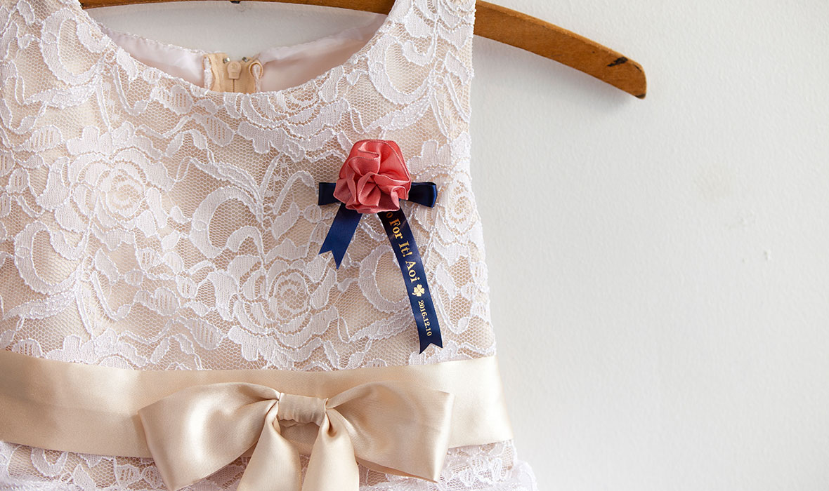 A bridesmaid's brooch pinned on their bridesmaid's dress, personalised with a Brother satin ribbon 