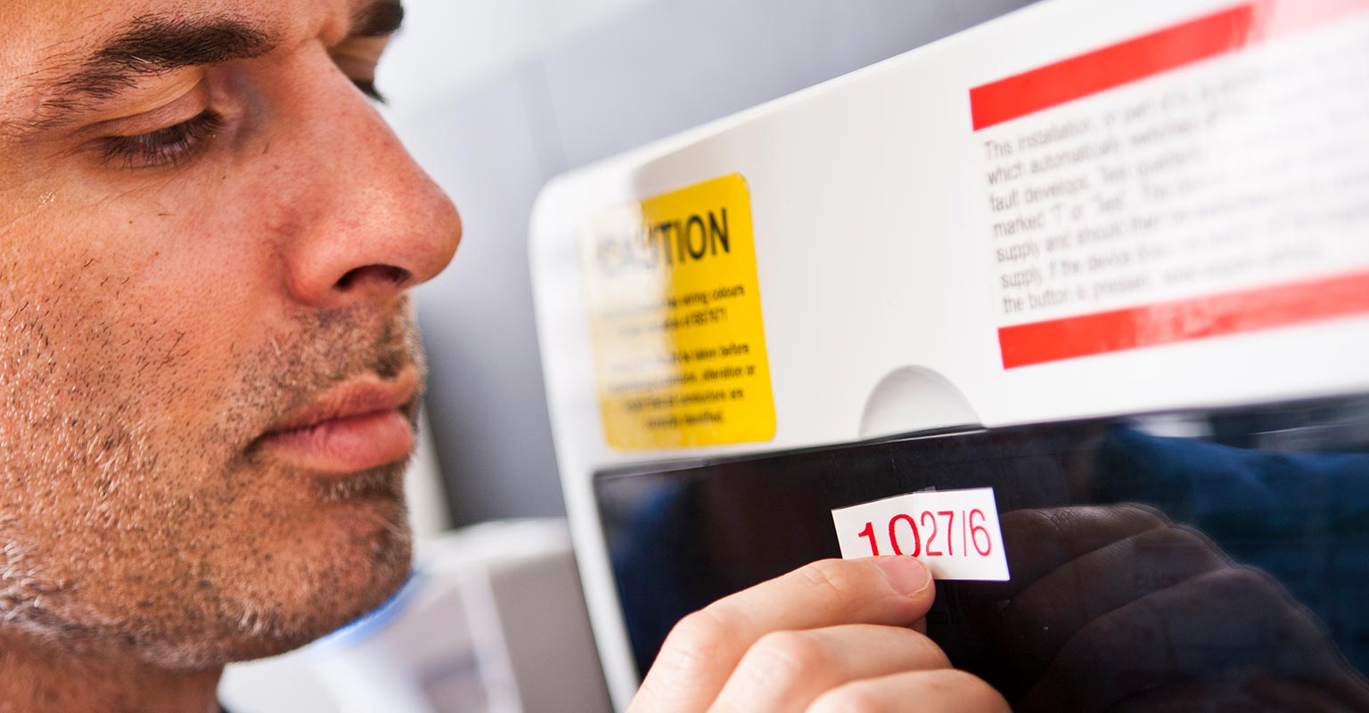 Man applying a label to a consumer unit