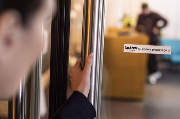 Klientas mato etiketę ant registratūros durų, kurioje prašoma lankytojų prisijungti