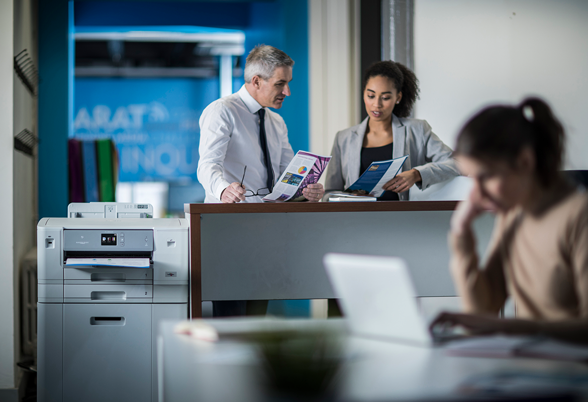 Brother HL-J6000DW printer in office setting surrounded by staff