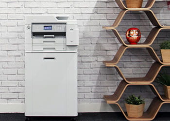 Printer on cabinet against grey brick wall next to hexagon shelving, plants, vase
