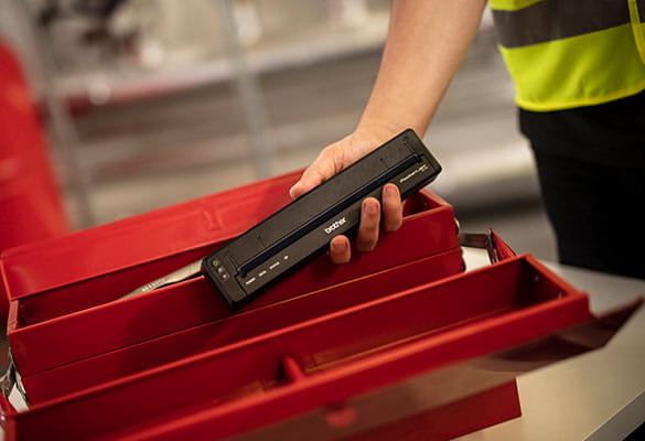 PocketJet-printer i hånden på en person ved en rød værktøjskasse