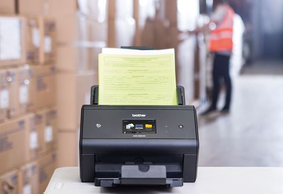 Stolní skener Brother ADS-3600W archivuje expediční poznámky ve skladu, krabice, muž v pracovní vestě