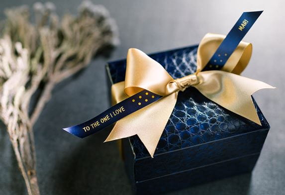 A blue gift box and ribbon with a gold bow