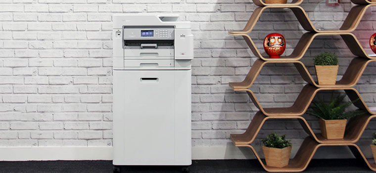 Printer on a cabinet against grey brick wall with hexagon shaped shelving, plants, vase