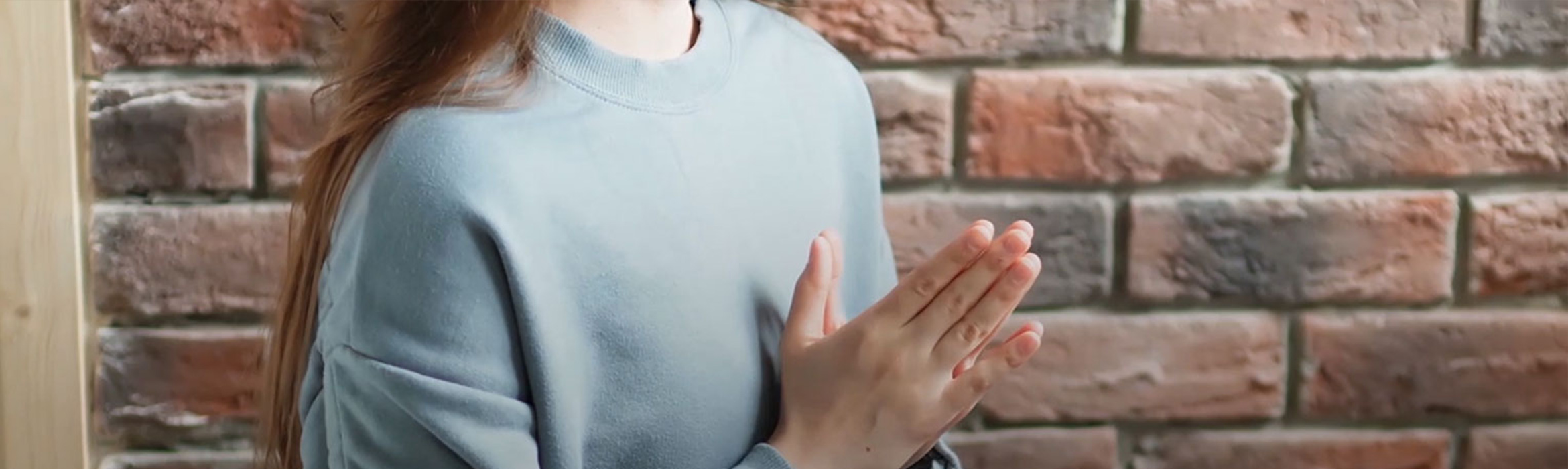 Žena sedí se sepnutýma rukama