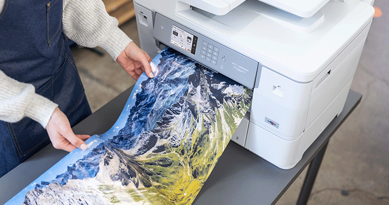 Large format paper of lanscape on gloss paper being printed from printer