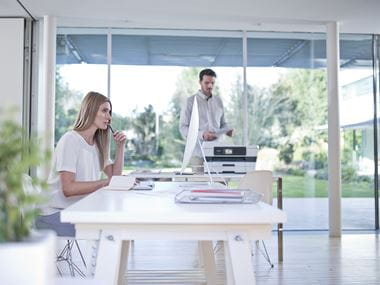 Muž a žena v domácí kanceláři s tiskárnou na stole