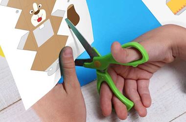 Child using scissors cutting out picture of dog