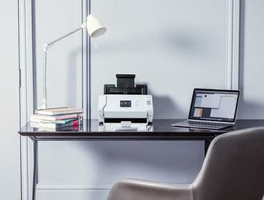 Brother skener na drvenom uredskom stolu s bijelom lampom i laptopom