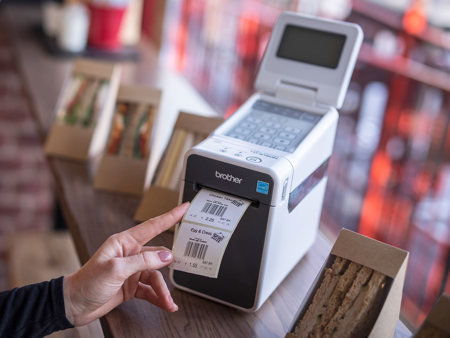 Brother TD-2000 desktop label printer with barcode label being printed