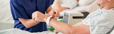 pielęgniarka zakłada pacjentowi opaskę na rękę