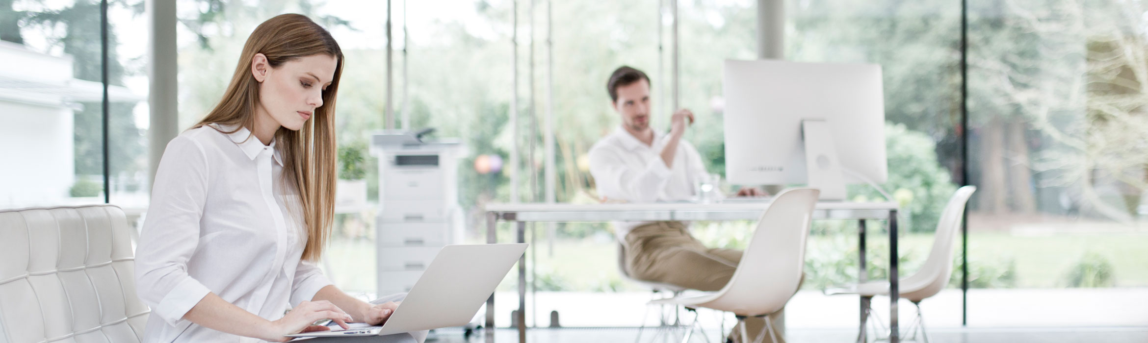 Lady on laptop with partner in the background