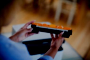 A woman holds a Brother printer toner cartridge - the image is blurred