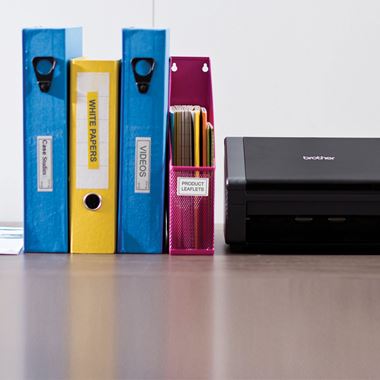 4 different colours folders standing next to a black brother printer