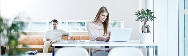 Frau sitzt an einem Schreibtisch, vor einem Laptop