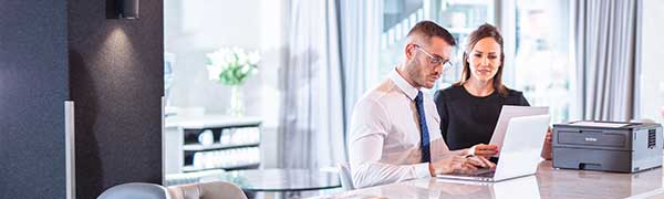 homme et femme assis au bureau sur un ordinateur portable