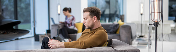 homme assis sur un canapé travaillant sur une tablette