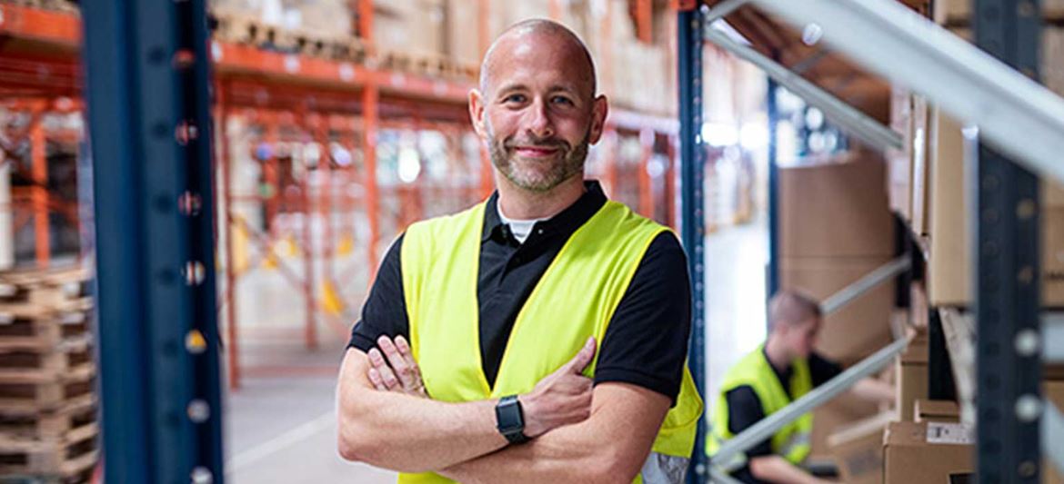 Man smiling wearing hi-vis vest in warehouse