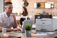 Man sat at desk with multifunction printer on desk