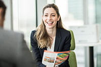 Usmívající se žena sedí v kanceláři s barevnou tiskárnou v pozadí