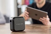 Moški s tablico in P-touch Cube Plus, ki ima baterijo