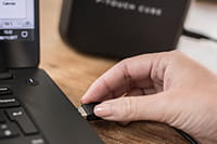 Ruka koja puni P-touch Cube Plus putem USB ulaza na računalu