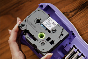 Someone inserting a labelling tape cassette into a P-touch handheld label printer