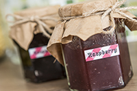 Two jam jars with string tied brown paper lids identified by printed labels