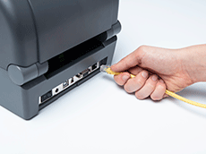 Yellow ethernet cable being put in TD-4T printer by hand