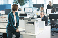 Women in green jacket sat on desk with professional 3 in 1 mono laser printer