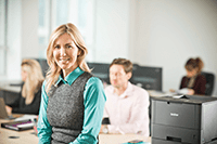 Business woman with blonde hair sitting on a desk with brother printer next to her