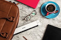 Brother DS-640 mobilni dokumentni skener, očala, kava, usnjena torba za prenosnik, svinčnik, tablica, roza zvezek