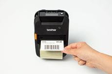 Rankoje laikoma nulupta lentynos krašto etiketė, atspausdinta Brother RJ-3200 mobiliuoju spausdintuvu
