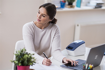 Office worker at her desk looking satisfied with her Brother QL-600B label printer