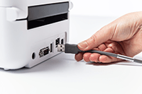 Hand inserting USB cable in to back of Brother TD-4550DNWB desktop label printer