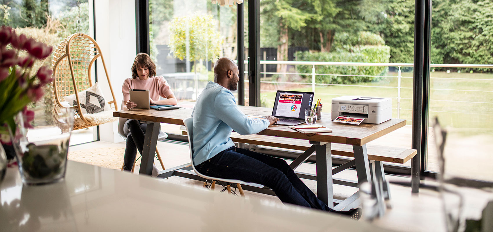 Couple sat at table working on laptop and tablet