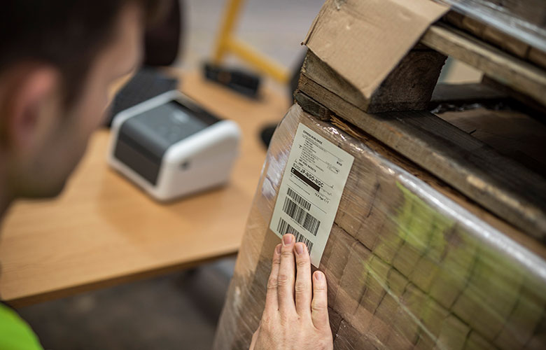 Mand, der sætter en fragtlabel på en kasse