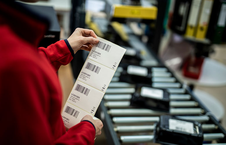 Worker holding product labels up in front of assembly line