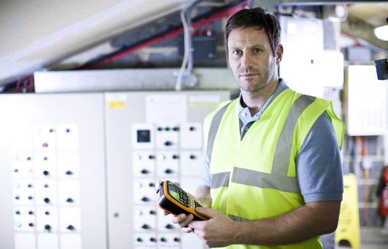 Male electrician in front of a distribution board, holding a Brother P-touch label printer