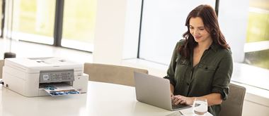 Une jeune femme travaille au sein d'un bureau aéré, équipée d'un ordinateur portable et d'une imprimante  multifonction