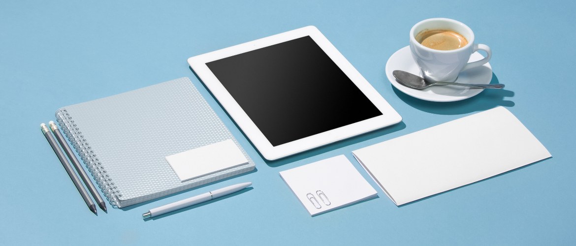 Les outils indispensables du télétravailleur sont réunis, à savoir un bloc notes, des crayons, une tablette et un expresso.