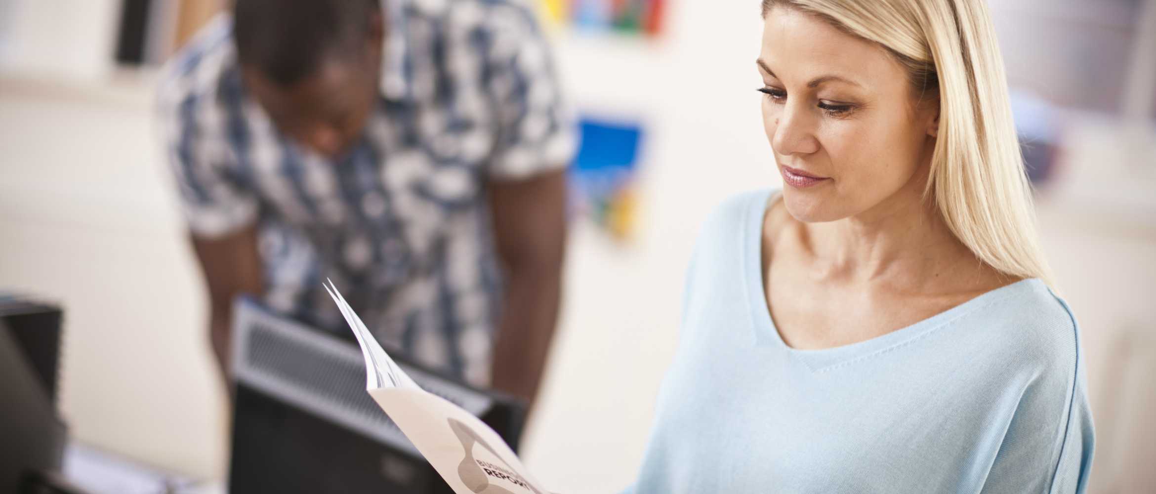 Une femme blonde lisant un document imprimé au format livret 