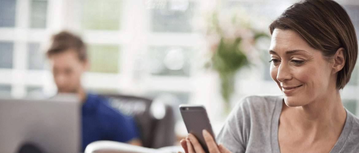 Une femme souriante utilise son smartphone dans le cadre de son environnement professionnel.