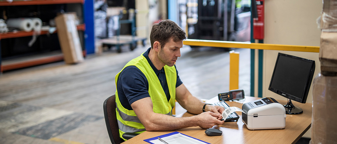 Un employé travaillant dans un entrepôt imprime une étiquette d'expédition. 