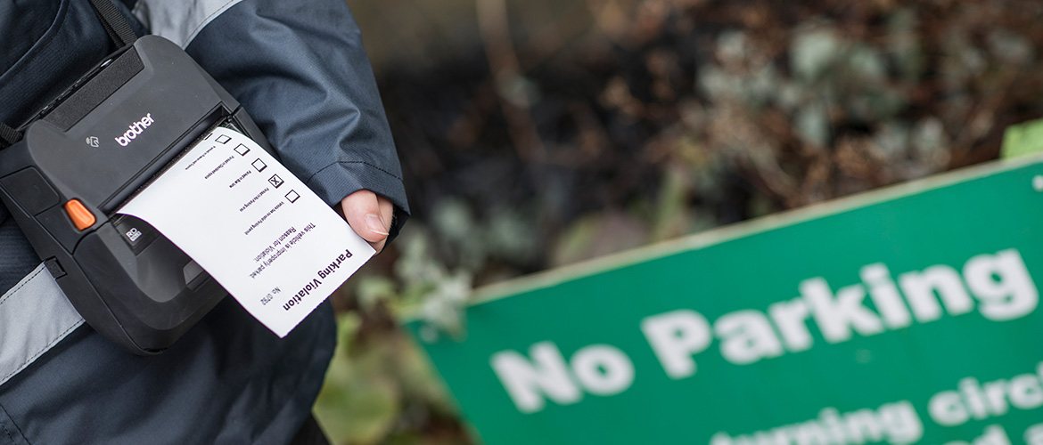 Un agent tenant une imprimante portable RJ de Brother en bandoulière imprime un ticket.