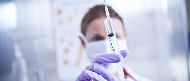 Un médecin de l'hôpital portant un masque facial tient une seringue contenant un médicament ou un vaccin.