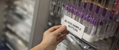 Une sélection de flacons d'échantillons de sang ont été étiquetés dans un environnement de soins de santé ou de tests hospitaliers. L'étiquette adhésive est appliquée par un membre du personnel médical.