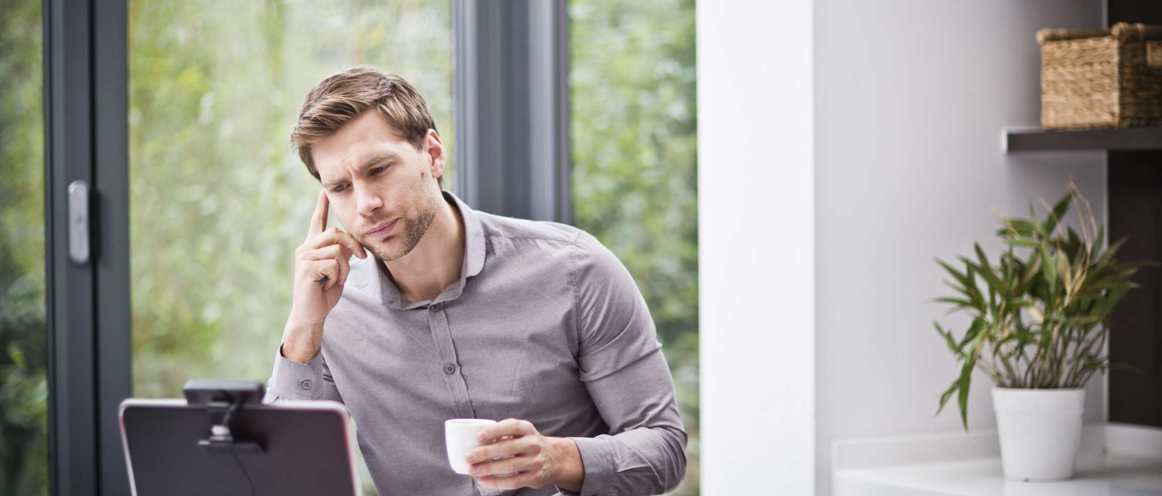 Dans cette nouvelle scène de travail à distance hybride, un homme est assis à son bureau à domicile et son ordinateur portable est équipé d'une webcam.
