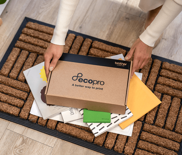Femme ramassant sa boîte Ecopro et des lettres sur un paillasson